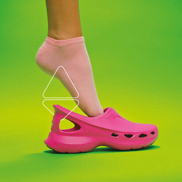 Pie con calcetín rosa calzando zapatos EASYLITE rosa sobre fondo verde.