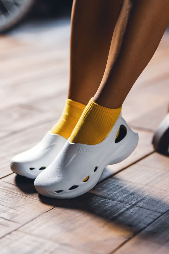 Profesional caminando con zapatos EASYLITE grises sobre suelo de madera.