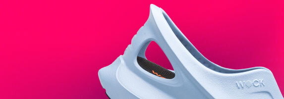 Primer plano del talón de los zapatos EASYLITE blancos sobre fondo verde.